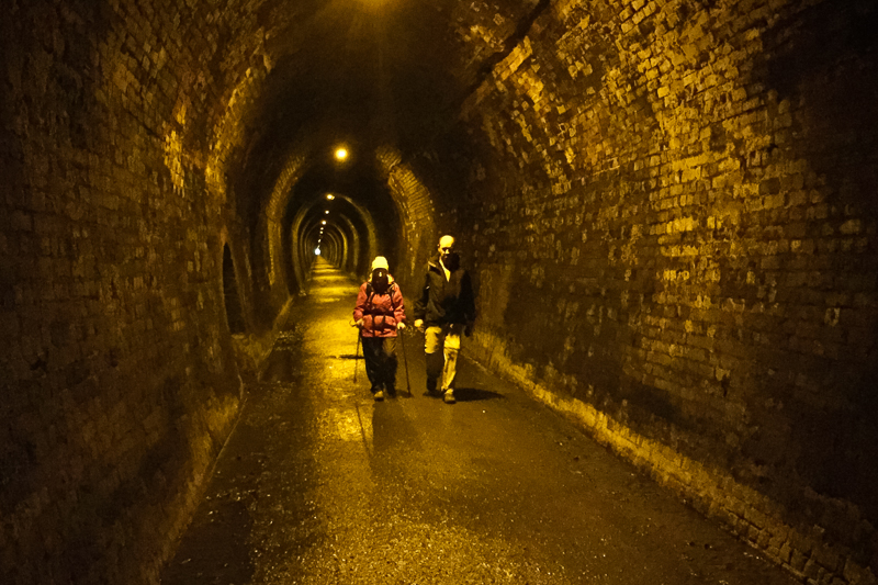 Hikers walk through the disused railway tunnel on the Karangahake Gorge Walkway