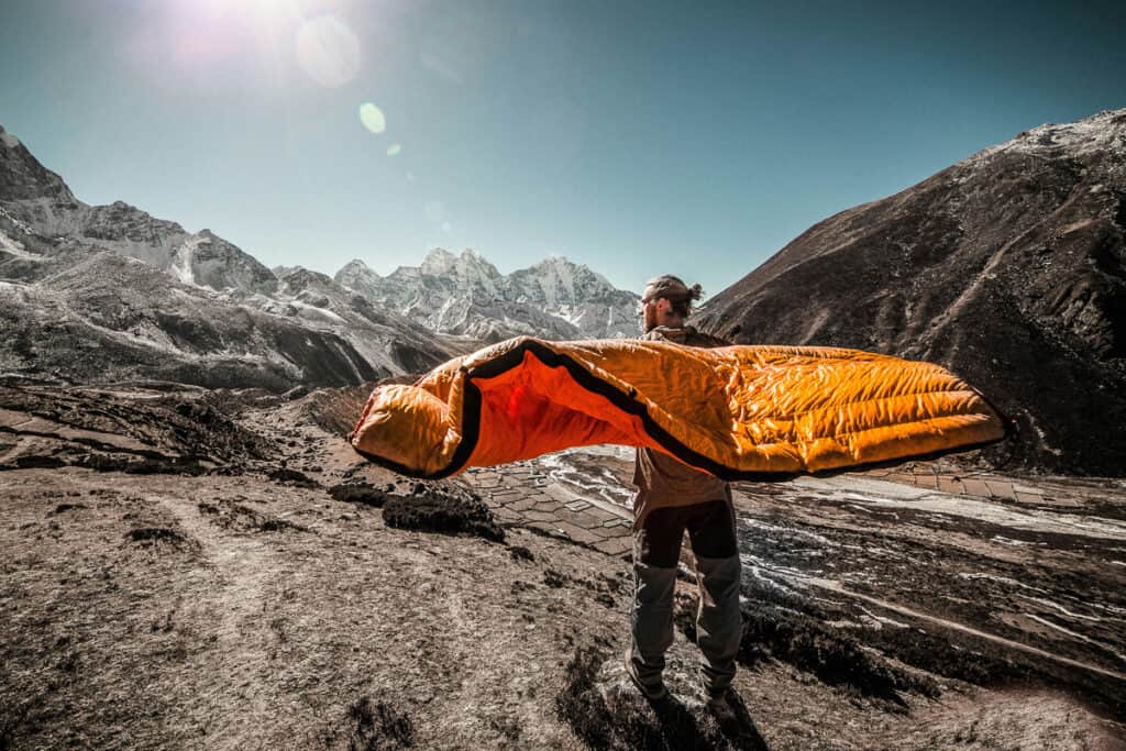 how much should a backpacking sleeping bag weigh? hiker with sleeping bag in mountains